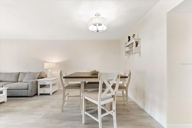 dining room featuring a textured ceiling and light wood-type flooring