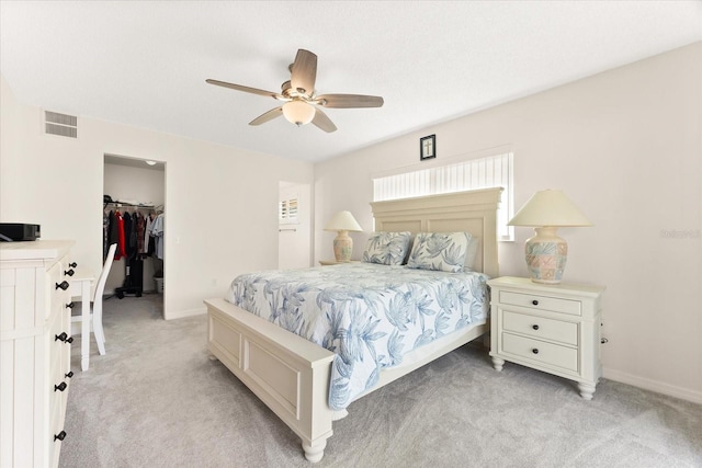 bedroom with a closet, a spacious closet, ceiling fan, and light colored carpet