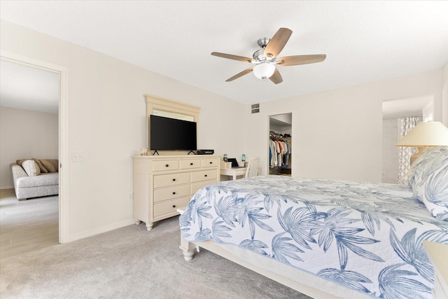 carpeted bedroom featuring a spacious closet, a closet, and ceiling fan