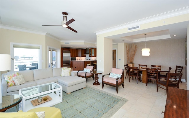 tiled living room featuring a raised ceiling, ornamental molding, and ceiling fan