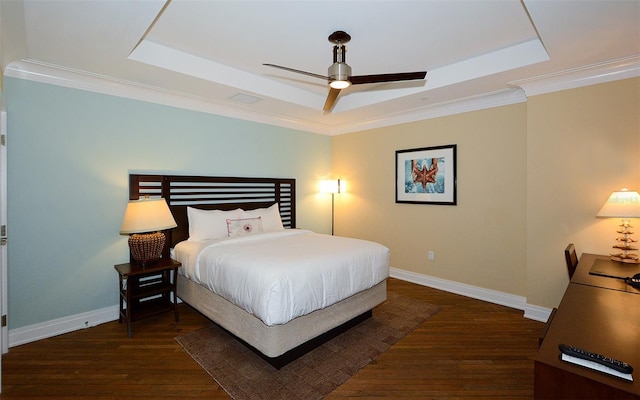 bedroom with a tray ceiling, ornamental molding, ceiling fan, and dark hardwood / wood-style floors