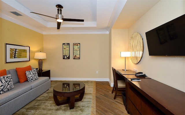 living room featuring a raised ceiling, ceiling fan, and light wood-type flooring