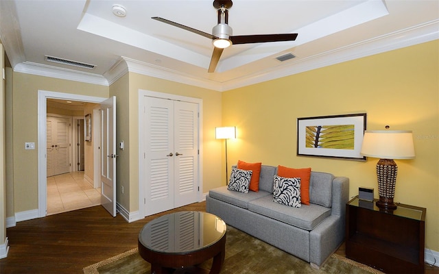 living room with a raised ceiling, ornamental molding, ceiling fan, and hardwood / wood-style flooring