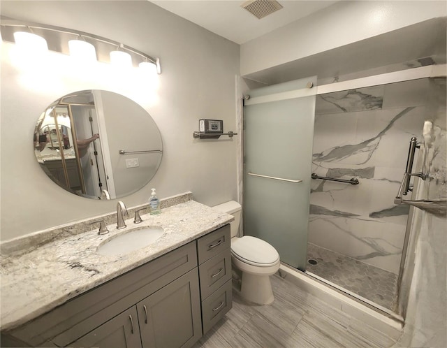 bathroom featuring vanity, toilet, and a shower with shower door