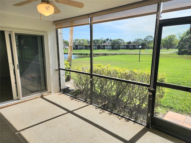 unfurnished sunroom with ceiling fan and a water view