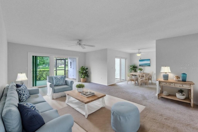 carpeted living room with a textured ceiling and ceiling fan