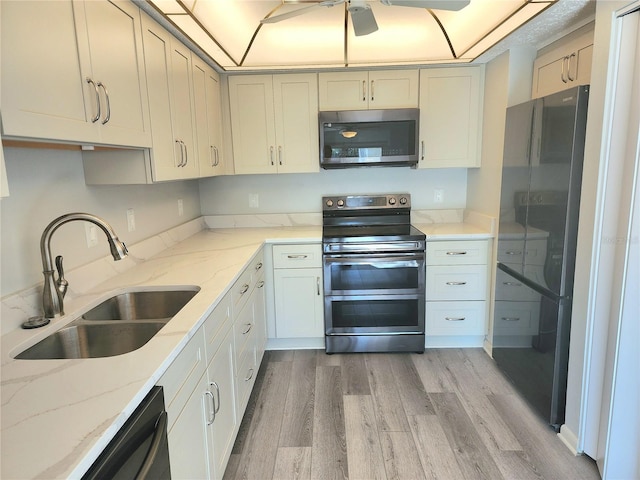 kitchen with light stone counters, sink, hardwood / wood-style flooring, and appliances with stainless steel finishes