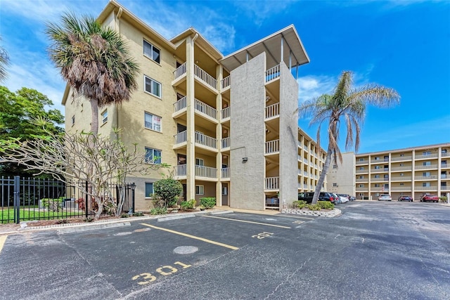 view of building exterior with uncovered parking and fence