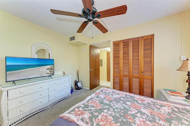 carpeted bedroom with a closet, ceiling fan, and a textured ceiling