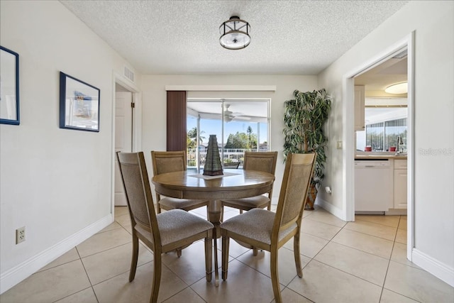 dining space with a textured ceiling, light tile flooring, ceiling fan, and sink