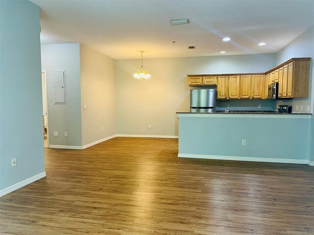 kitchen with appliances with stainless steel finishes, decorative light fixtures, an inviting chandelier, and hardwood / wood-style flooring