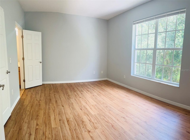 empty room featuring vaulted ceiling and light wood-type flooring