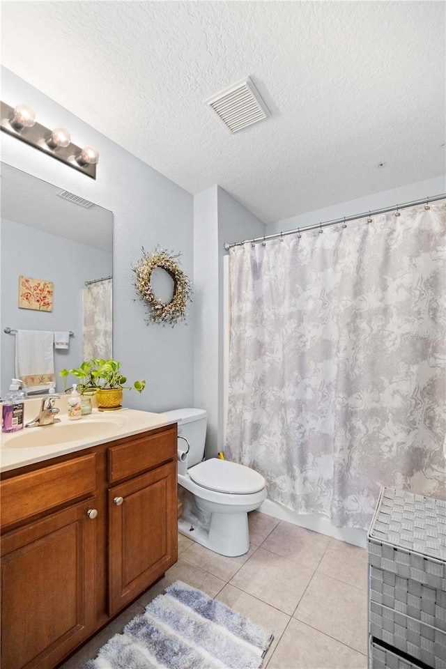 bathroom with a textured ceiling, tile floors, toilet, and vanity