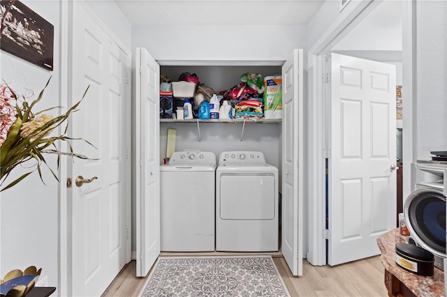 clothes washing area with independent washer and dryer and light hardwood / wood-style flooring