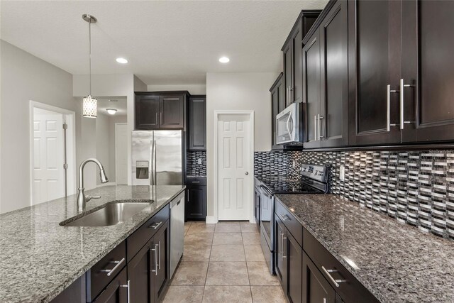 kitchen featuring appliances with stainless steel finishes, dark brown cabinetry, sink, pendant lighting, and stone countertops