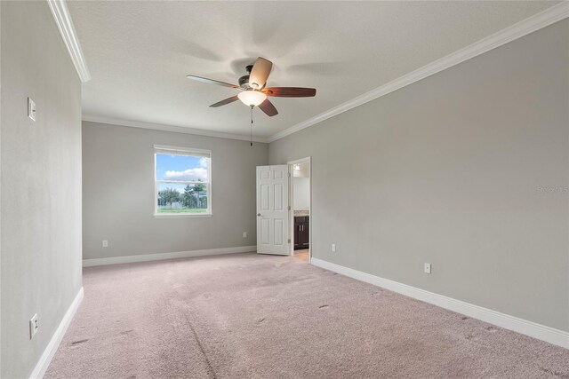 empty room with ceiling fan, crown molding, and light carpet