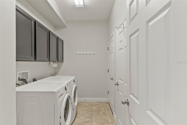 washroom with separate washer and dryer, light tile patterned floors, and cabinets