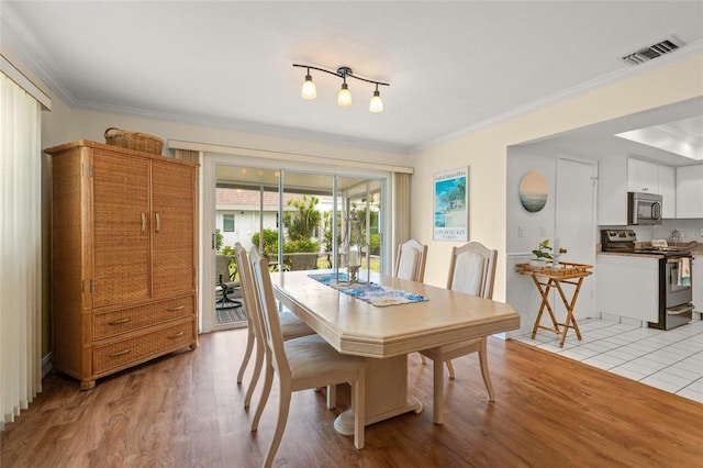 dining area with light hardwood / wood-style floors and ornamental molding