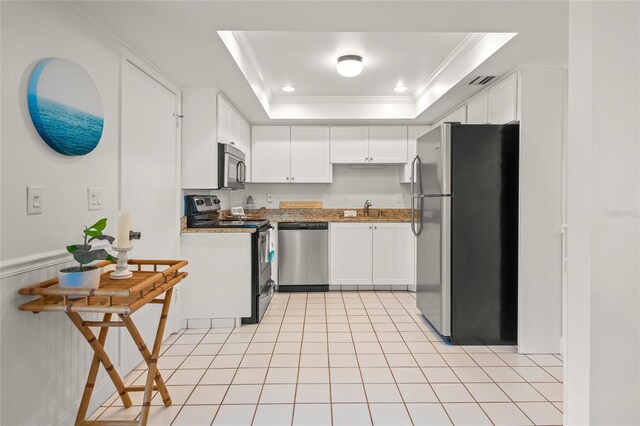 kitchen featuring white cabinetry, appliances with stainless steel finishes, a raised ceiling, ornamental molding, and sink