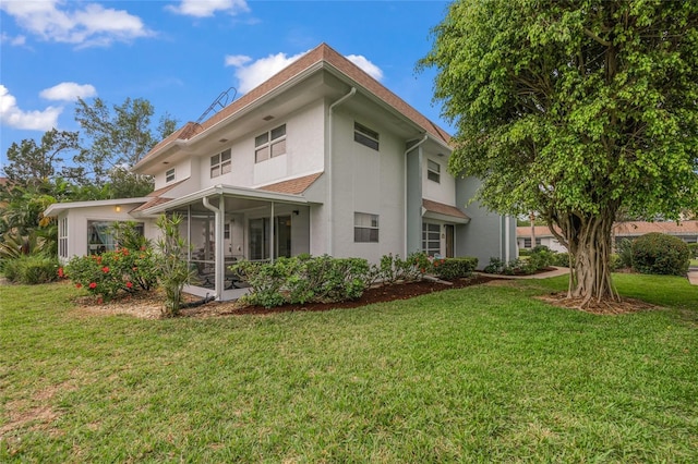 rear view of property featuring a sunroom and a lawn