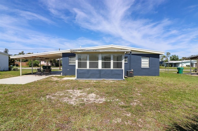 rear view of property with central air condition unit, a yard, and a carport