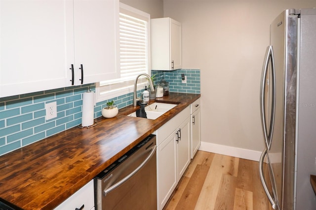 kitchen featuring wood counters, light wood-type flooring, stainless steel appliances, and sink