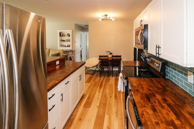 kitchen with appliances with stainless steel finishes, tasteful backsplash, light hardwood / wood-style floors, white cabinets, and wood counters