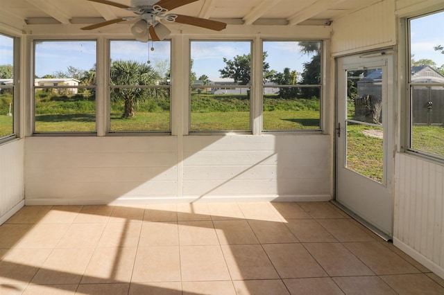 unfurnished sunroom featuring ceiling fan and beamed ceiling