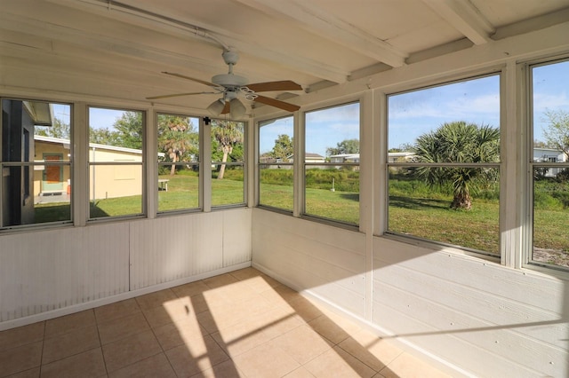 unfurnished sunroom with beamed ceiling, ceiling fan, and a wealth of natural light