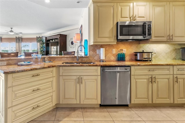 kitchen featuring light stone countertops, ceiling fan, sink, stainless steel appliances, and light tile floors