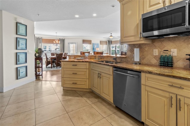 kitchen with dark stone counters, backsplash, appliances with stainless steel finishes, and ceiling fan with notable chandelier