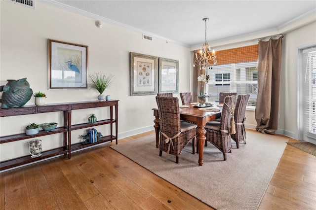 dining space featuring plenty of natural light, a chandelier, crown molding, and light hardwood / wood-style flooring