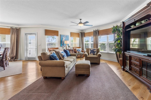 living room with a healthy amount of sunlight, ceiling fan, light wood-type flooring, and crown molding