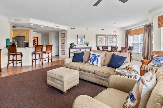 living room with ornamental molding, ceiling fan with notable chandelier, and light hardwood / wood-style flooring