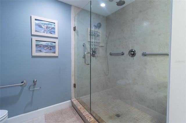 bathroom featuring tile floors, a shower with shower door, and toilet