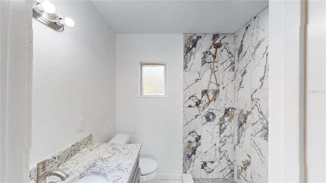 bathroom featuring vanity, a tile shower, and toilet