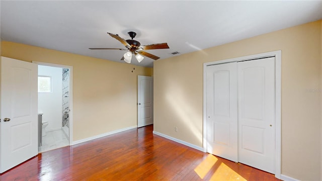 unfurnished bedroom with ensuite bath, a closet, ceiling fan, and dark hardwood / wood-style floors