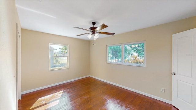 spare room featuring a healthy amount of sunlight, ceiling fan, and dark hardwood / wood-style flooring