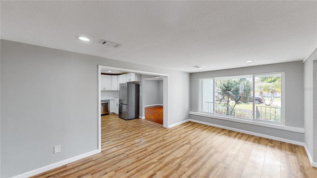 empty room featuring a textured ceiling and light wood-type flooring