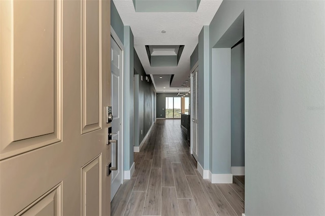 corridor with a textured ceiling and light hardwood / wood-style floors