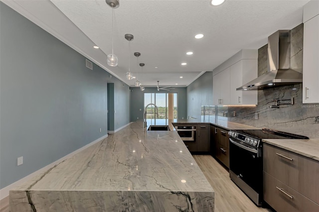 kitchen featuring backsplash, sink, stainless steel appliances, light wood-type flooring, and wall chimney range hood