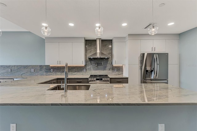 kitchen with pendant lighting, stainless steel appliances, wall chimney exhaust hood, and sink