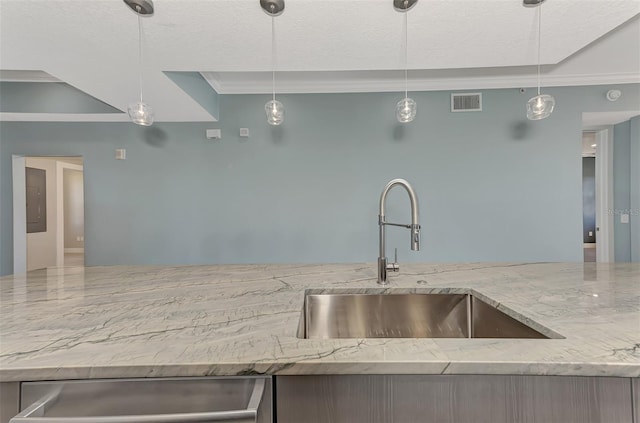 kitchen featuring hanging light fixtures, light stone counters, crown molding, and sink