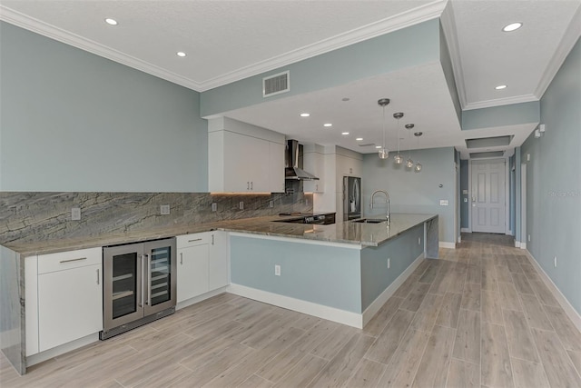 kitchen with white cabinetry, wall chimney exhaust hood, and sink