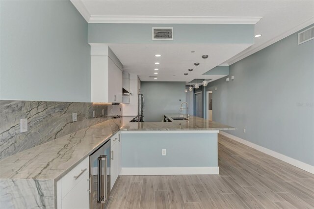 kitchen featuring light hardwood / wood-style floors, white cabinetry, backsplash, light stone counters, and sink