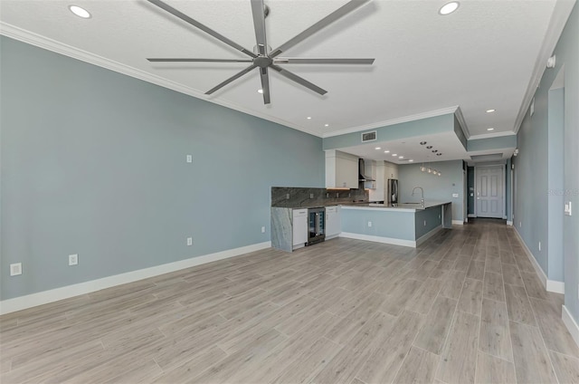 unfurnished living room featuring light hardwood / wood-style floors, ceiling fan, beverage cooler, ornamental molding, and sink