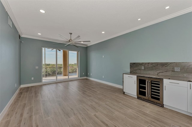 interior space featuring light hardwood / wood-style floors, ceiling fan, white cabinetry, and crown molding