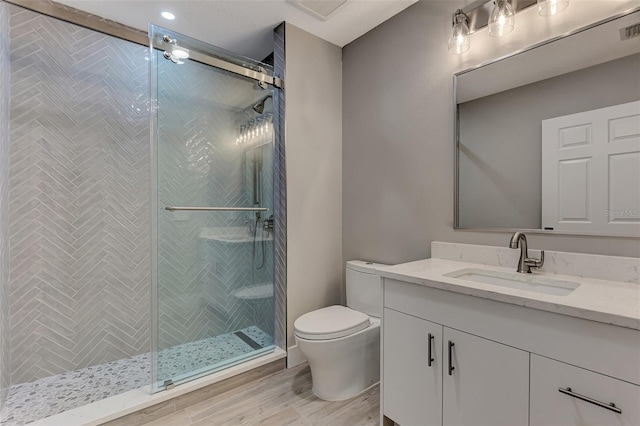 bathroom featuring toilet, a shower with shower door, and vanity