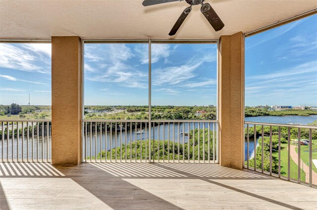 sunroom featuring ceiling fan and a water view