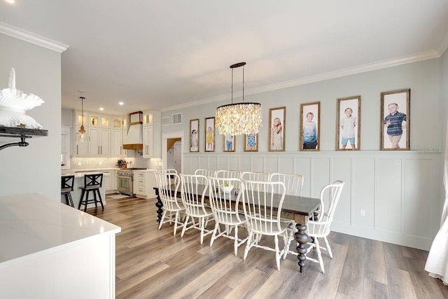 dining room with a chandelier, light hardwood / wood-style floors, and crown molding